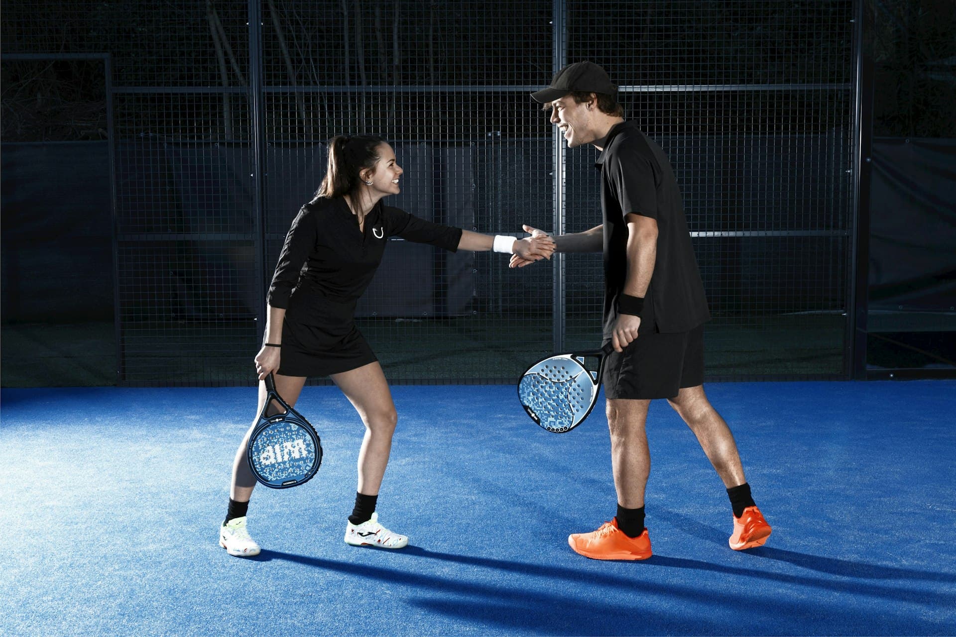 Deux joueurs échangent sur un terrain de padel indoor